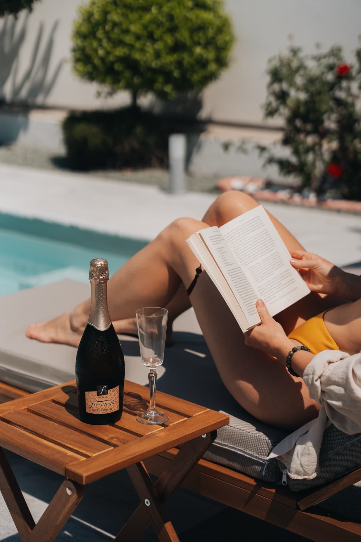 Guest reading by the pool with champagne — luxury villa lifestyle